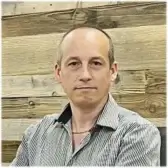 Professor Antonino La Rocca in a striped shirt against a wooden wall